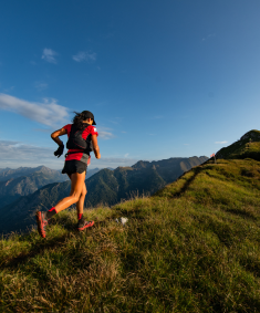 A woman trail running along a mountain ridge