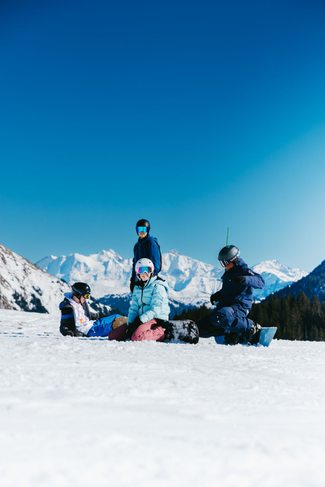 Snowboarders stopped on a slope during an Evolution 2 ski lesson at La Clusaz.