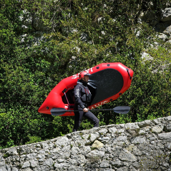 A man carries his packraft, ready to embark on an adventure