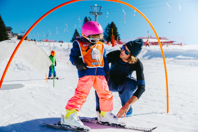 Enfant au jardin d'enfant de ski à La Clusaz avec Evolution 2 et son moniteur de ski