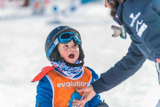 Child taking a beginner ski lesson in Tignes, wearing a helmet and goggles