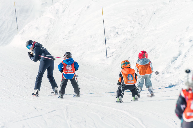 Cours de ski Evolution 2 avec monitrice et élèves enfants derrière