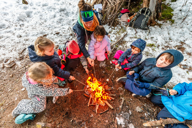 Group of children around a wood fire, eating toasted marshmallows