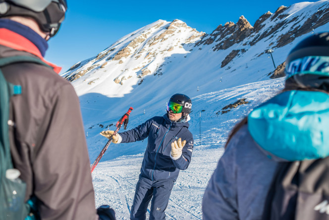 moniteur de ski Evolution 2 donnant des explications sur les pistes à ses élèves adultes