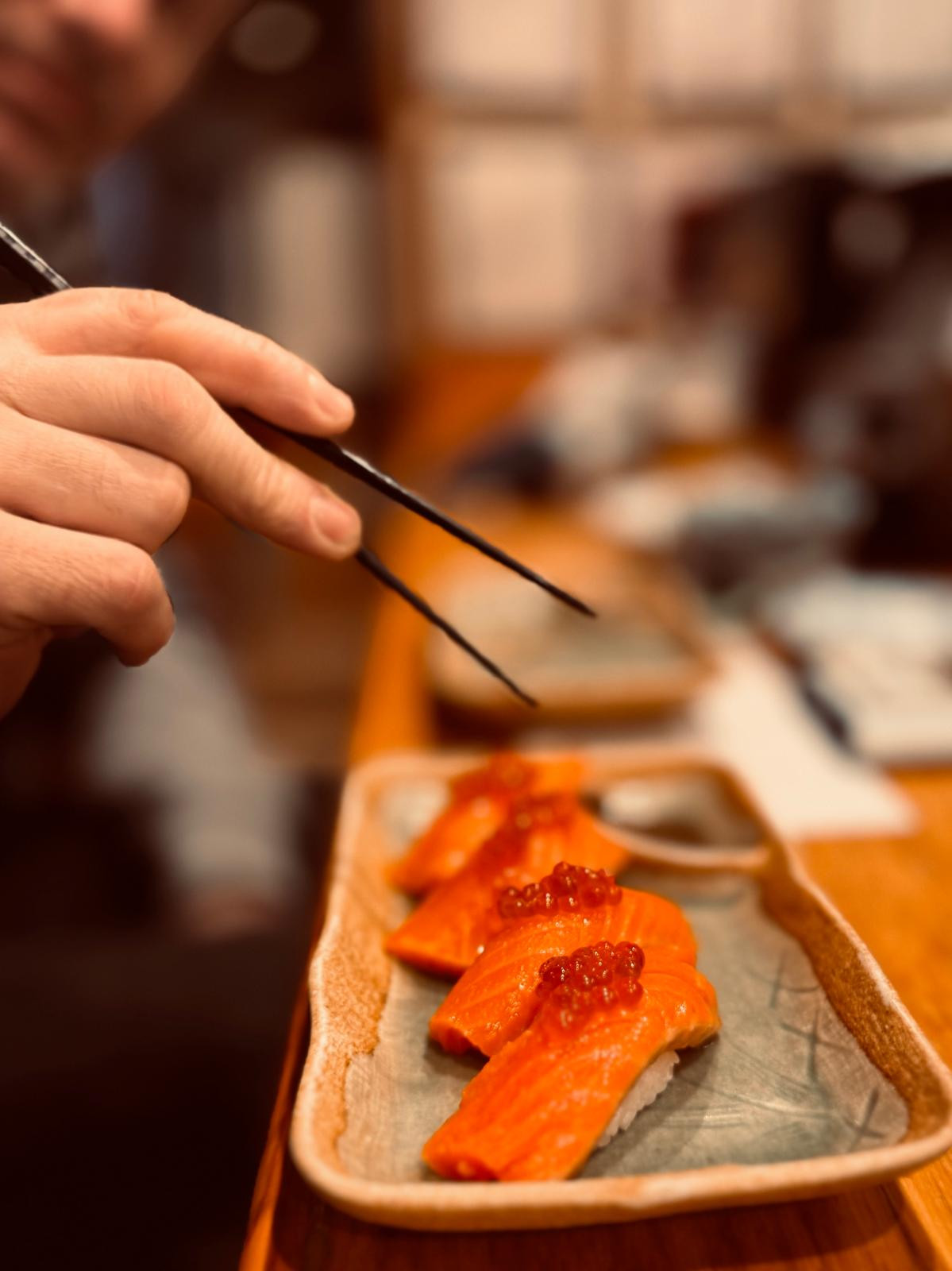 alt="A man is enjoying some Japanese specialities – sushi – whilst on a skiing holiday in Japan