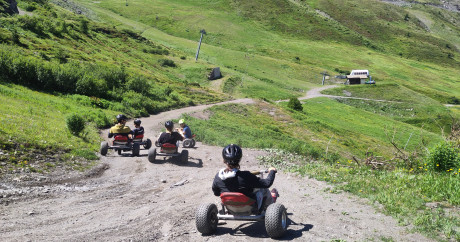 Mountain Kart à Val Cenis : participant en kart tout-terrain descendant une piste de montagne avec vue sur les sommets de Haute Maurienne.