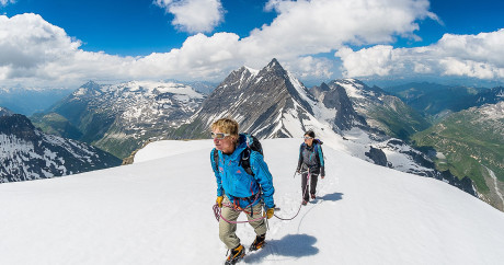 Participants équipés de crampons et harnais lors d'une randonnée glaciaire sur le glacier de la Grande Motte à Tignes accompagnés d'un guide de haute montagne.